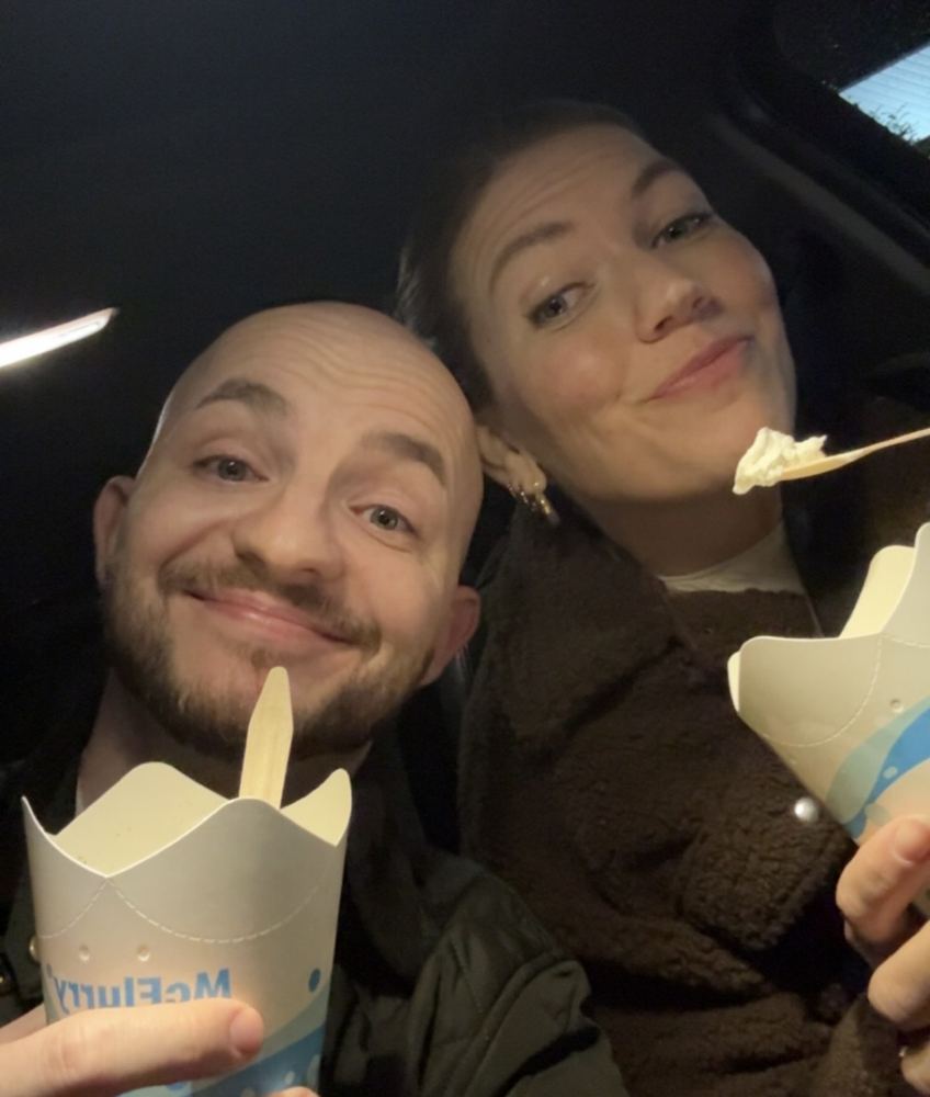 Mareike und Pierre im Auto, jeder mit einem McFlurry in der Hand, beide lachen in die Kamera